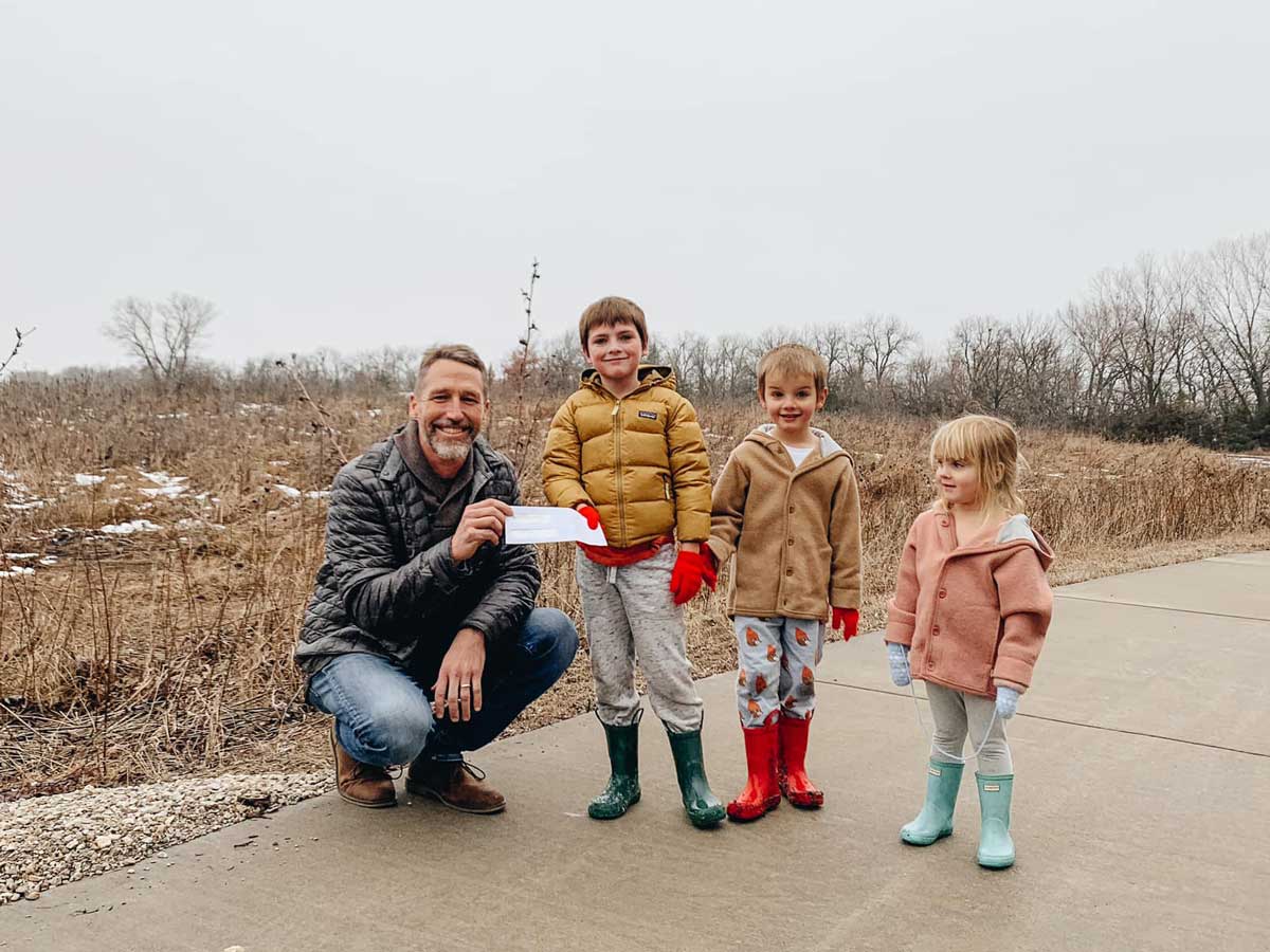 Three of the youngest members of the Gaeddert family presenting a check to Brad Guhr at Dyck Arboretum of the Plains